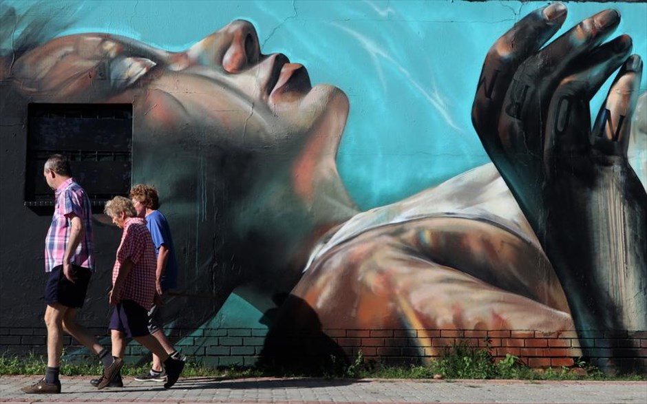 Street art στο Γιοχάνεσμπουργκ. Κόσμος, στο&nbsp;Γιοχάνεσμπουργκ της Νότιας Αφρικής, περνάει μπροστά από τοίχο ζωγραφισμένο στο πλαίσιο του&nbsp;Westdene Graffiti Project .&nbsp;