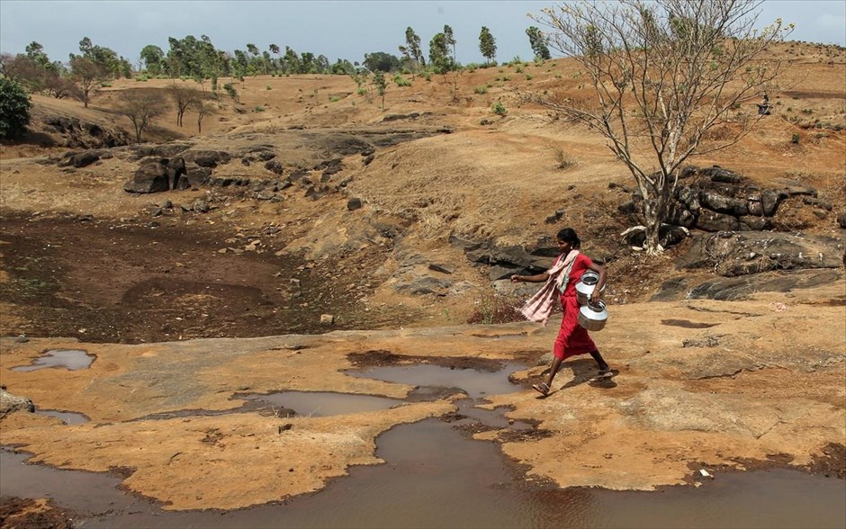 Δύσκολες συνθήκες στην Ινδία. Μία γυναίκα προσπαθεί να φιλτράρει και να μεταφέρει νερό δίπλα από μολυσμένη λίμνη στην  περιοχή Thane, στην Ινδία. 