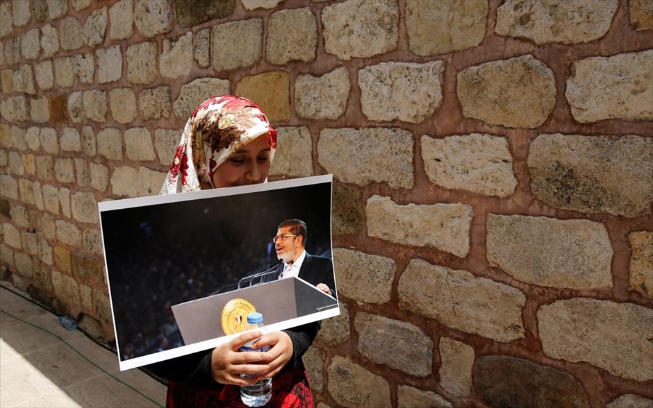Θλίψη για τον Μοχάμεντ Μόρσι. Μία κοπέλα κρατώντας τη φωτογραφία του  πρώην προέδρου της Αιγύππτου Μοχάμεντ Μόρσι συμμετέχει σε συμβολική κηδεία στο Φατίχ Τζαμί της Κωνσταντινούπολης. Ο πρώτος δημοκρατικά εκλεγμένος ηγέτης της Αιγύπτου κατέρρευσε και άφησε την τελευταία του πνοή σε αίθουσα δικαστηρίου στο Κάιρο χθες, έξι χρόνια μετά την ανατροπή του με πραξικόπημα και την επιστροφή της χώρας στην απολυταρχία.