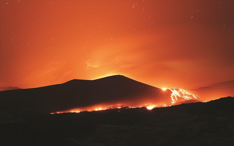 Η δύναμη ενός ακίνδυνου γίγαντα. Στιγμιότυπο όπου η άγρια ομορφιά της φύσης προκαλεί δέος και θαυμασμό συγχρόνως. Το ηφαίστειο της Αίτνας στη Σικελία εξακολουθεί να εκτοξεύει την πύρινη λάβα του σχεδόν 10 ημέρες μετά την έκρηξή του. Είναι το μεγαλύτερο και υψηλότερο ενεργό ηφαίστειο στην Ευρώπη, καθώς ξεπερνά τα 3.350 μέτρα, ενώ είναι τρεις φορές μεγαλύτερο από τον Βεζούβιο. Παρά το γεγονός ότι είναι ιδιαίτερα «κινητικό» (η προηγούμενη έκρηξή του ήταν τον περασμένο Δεκέμβριο), δεν θεωρείται από τους επιστήμονες πολύ επικίνδυνο, γι’ αυτό άλλωστε οι πλαγιές του και οι περιοχές γύρω από αυτό είναι κατοικήσιμες και πολλές εκτάσεις καλλιεργήσιμες.&nbsp;