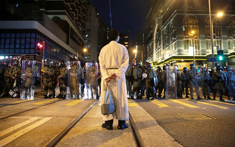 Σαββατοκύριακο εντάσεων ξανά στο Χονγκ Κονγκ. Ένας ιερέας διακρίνεται μπροστά από αστυνομικές δυνάμεις κατά τη διάρκεια διαδηλώσεων στο Χονγκ Κονγκ. Έπειτα από ένα ακόμη Σαββατοκύριακο βίαιων επεισοδίων, η επικεφαλής της κυβέρνησης Κάρι Λαμ προειδοποίησε σήμερα ότι οι διαδηλώσεις των τελευταίων μηνών στην άλλοτε βρετανική αποικία ωθούν την πόλη στα όρια μιας «εξαιρετικά επικίνδυνης κατάστασης» καθώς θέτουν υπό αμφισβήτηση την κυριαρχία της Κίνας.