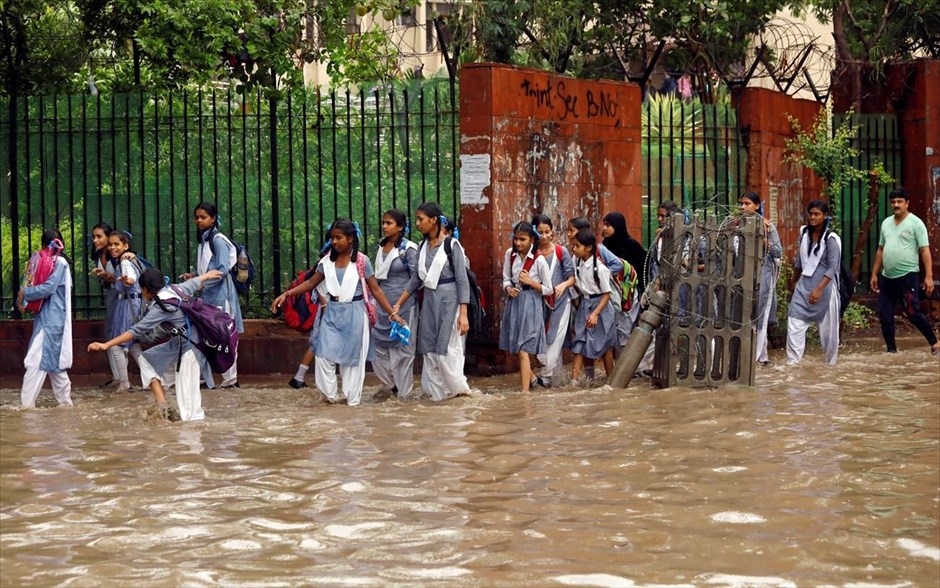 Βροχοπτώσεις στην Ινδία. Μαθήτριες προσπαθούν να περάσουν από πλημμυρισμένο δρόμο έπειτα από έντονη βροχόπτωση στο Νέο Δελχί (Ινδία). 