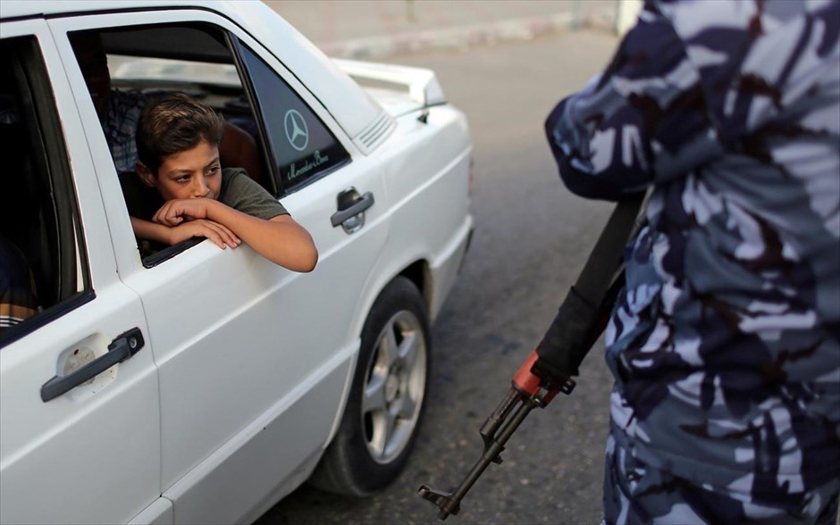 Περιμένοντας τον έλεγχο. Ένα αγόρι κοιτάει ένοπλο μέλος της Χαμάς που φρουρεί σημείο ελέγχου στην λωρίδα της Γάζα