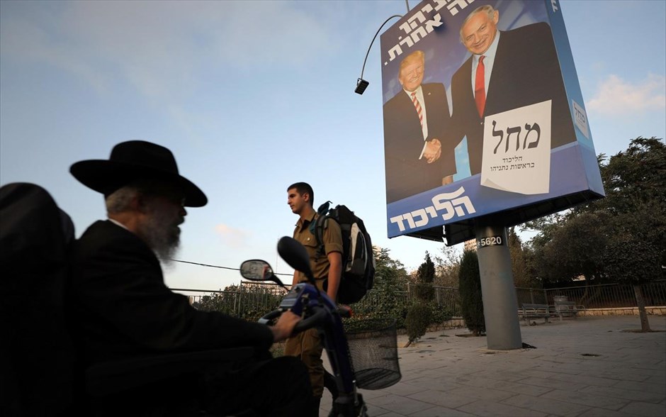 Ισραήλ: Εκλογές - δημοψήφισμα για το πολιτικό μέλλον του Νετανιάχου. Υπερορθόδοξος Εβραίος στην Ιερουσαλήμ περνάει μπροστά από αφίσα με τον Ισραηλινό πρωθυπουργό Μπενιαμίν Νετανιάχου και το Αμερικανό πρόεδρο Ντόναλντ Τραμπ. Οι Ισραηλινοί προσέρχονται σήμερα, για δεύτερη φορά μέσα σε πέντε μήνες, στις κάλπες για τις βουλευτικές εκλογές. Η εκλογική αναμέτρηση προμηνύεται ως μια μάχη στήθος με στήθος μεταξύ του Νετανιάχου και του πρώην αρχηγού του στρατού Μπένι Γκαντς.