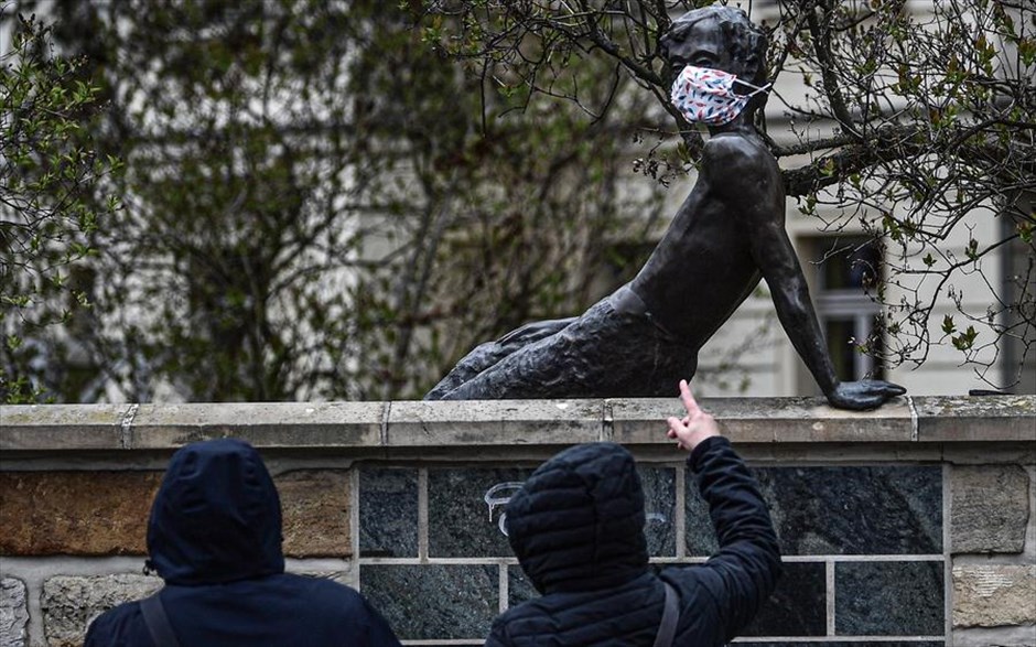 Μάσκες και στα αγάλματα . Περαστικοί στο κέντρο της Δρέσδης παρατηρούν ένα άγαλμα στο οποίο έχει τοποθετηθεί ιατρική μάσκα.&nbsp;