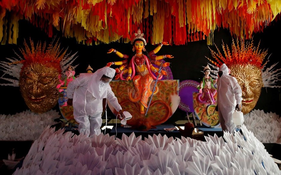 Απολύμανση πριν το φεστιβάλ Durga Puja. Άτομα που φορούν&nbsp;προστατευτικό εξοπλισμό απολυμένουν ένα "pandal" δίπλα σε ένα είδωλο της&nbsp;θεάς Durga για το επερχόμενο φεστιβάλ Durga Puja στην Καλκούτα, Ινδία