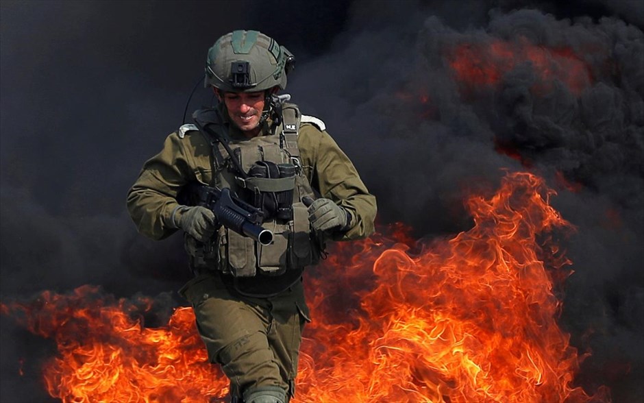 Άλλη μια μέρα στην Δυτική όχθη. Ισραηλινός στρατιώτης προσπαθεί να ξεφύγει απο τις φλόγες καθώς οι Παλαιστίνιοι διαμαρτύρονται εναντίον εβραϊκών οικισμών στη Δυτική Όχθη, Ισραήλ