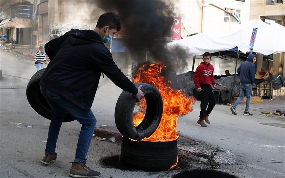 Συγκρούσεις στη Δυτική Όχθη. Ένας νεαρός Παλαιστίνιος βάζει ένα ελαστικό αυτοκινήτου στη φωτιά που καίει, κατά τη διάρκεια συγκρούσεων με ισραηλινές δυνάμεις, στη Χεβρώνα της Δυτικής Όχθης.