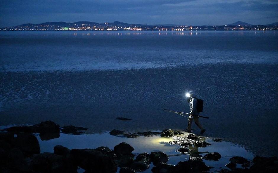 Νυχτερινό ψάρεμα. Άντρας με φακό στο κεφάλι πάει για νυχτερινό ψάρεμα στο Δουβλίνο