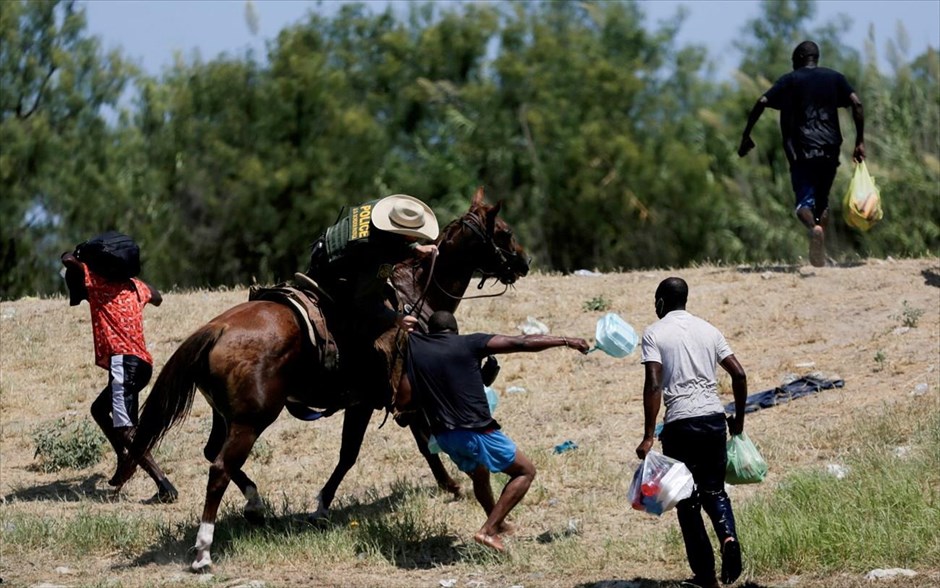 POY 2021. Ένας αξιωματικός της συνοριοφυλακής των ΗΠΑ αρπάζει από τη μπλούζα&nbsp;έναν μετανάστη που προσπαθεί να επιστρέψει στις Ηνωμένες Πολιτείες κατά μήκος του ποταμού Ρίο Γκράντε, αφού πέρασε από τις Ηνωμένες Πολιτείες στο Μεξικό για να αγοράσει τρόφιμα.Ο φωτογράφος του Reuters Daniel Becerril σχολιάζει: "Οι Ηνωμένες Πολιτείες κρατούσαν εκατοντάδες μετανάστες&nbsp;σε έναν καταυλισμό στο Del Rio του Τέξας. Πολλοί από αυτούς μου είπαν ότι αναγκάστηκαν να σταθούν σε μεγάλες ουρές στην έντονη ζέστη για να λάβουν μόνο ένα κομμάτι ψωμί και ένα μπουκάλι νερό ανά άτομο κάθε μέρα.«Δεν μας δίνουν φαγητό. Θέλουν να μας εξαντλήσουν", μου είπαν οι μετανάστες. Πολλοί μετανάστες πέρασαν ξανά&nbsp;τον ποταμό Ρίο Γκράντε για να ψάξουν για τροφή και νερό στο Μεξικό. Στην αρχή, η συνοριοφυλακή των ΗΠΑ τους επέτρεψε να περάσουν τον ποταμό που χωρίζει τα δύο έθνη. Αργά το απόγευμα, οι μετανάστες έλαβαν εντολή να φύγουν από το ποτάμι και να επιστρέψουν στον καταυλισμό. Οι συνοριοφύλακες&nbsp;οδήγησαν τα άλογά τους κατά πάνω τους, κουνώντας κάτι που έμοιαζε με μαστίγιο. Άκουσα έναν από αυτούς να λέει:&nbsp;"Πήγαινε πίσω στη σκατένια χώρα σου." Όταν τράβηξα αυτή τη φωτογραφία, στεκόμουν στο ποτάμι με το νερό πάνω από τη μέση μου. Ένας συνοριοφύλακας&nbsp;έγειρε πάνω στο άλογό του και άρπαξε τη μπλούζα ενός μετανάστη από την Αϊτή που κράταγε σακούλες με τρόφιμα προσπαθώντας&nbsp;&nbsp;να διασχίσει το ποτάμι και να επιστρέψει στον καταυλισμό στις&nbsp;ΗΠΑ. Έμεινα στο ποτάμι μέχρι το σούρουπο τραβώντας περισσότερες φωτογραφίες, προσέχοντας να μην περάσω τη γραμμή των συνόρων και αποφεύγοντας τα επικίνδυνα ρεύματα που έχουν πνίξει πολλούς μετανάστες».