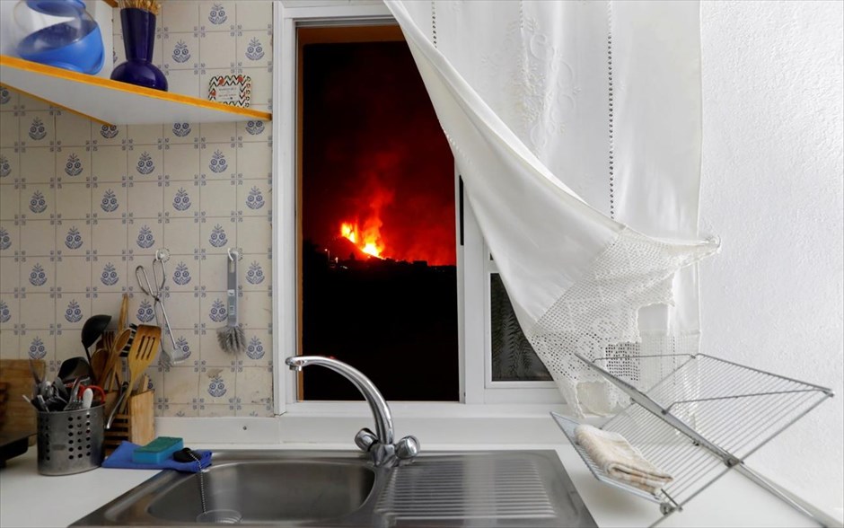 POY 2021. Η λάβα φαίνεται μέσα από το παράθυρο μιας κουζίνας μετά την έκρηξη ηφαιστείου στο Ελ Πάσο στην Λα Πάλμα της&nbsp;Ισπανίας.Ο φωτογράφος του Reuters Jon Nazca σχολιάζει: "Υπάρχει κάτι εκπληκτικά όμορφο και υπνωτιστικό όταν βλέπεις ένα ηφαίστειο να εκρήγνυται. Αλλά είναι εντελώς διαφορετικό να περνάς μέρα με τη μέρα δίπλα σε ένα ηφαίστειο, ακούγοντας τον απίστευτο θόρυβο που κάνει, το τρέμουλο του εδάφους, τα αέρια που κάνουν την αναπνοή τόσο δύσκολη και τη στάχτη που πέφτει συνεχώς στο κεφάλι σου. Τέσσερις μέρες μετά την έκρηξη, προσγειώθηκα στο ισπανικό νησί Λα Πάλμα. Προσπαθούσα να βρω κάπου να μείνω και τελικά βρήκα ένα σπίτι στα περίχωρα της πόλης. Ανησυχούσα για την ασφάλειά μου, το σπίτι ήταν πολύ κοντά στη ζώνη αποκλεισμού. Ωστόσο, είχε εκπληκτική θέα στο ηφαίστειο Cumbre Vieja, το τέλειο μέρος για έναν φωτορεπόρτερ. Ήθελα να τραβήξω μια εικόνα που να δείχνει τι βίωναν οι κάτοικοι της Λα Πάλμα. Μπόρεσα να έχω πρόσβαση στο διπλανό σπίτι με τον συνάδελφό μου Μιγκέλ Περέιρα. Πήγα κατευθείαν στο παράθυρο της κουζίνας και άρχισα να στήνω. Ο Μιγκέλ είχε αφήσει ένα ποτήρι νερό στο νεροχύτη και μου άρεσε το ανθρώπινο στοιχείο που έδινε - η ζεστασιά του σπιτιού σε αντίθεση με τη ζέστη του ηφαιστείου έξω. Είναι μια καθημερινή εικόνα, μια κουζίνα όπως μπορεί να έχει οποιοσδήποτε από εμάς, αλλά ενώ πλένεις πιάτα, έξω ένα ηφαίστειο εκρήγνυται. Η εικόνα είναι ανησυχητική, έως και απειλητική. Θα μπορούσε να είναι το σπίτι σου, η κουζίνα σου».