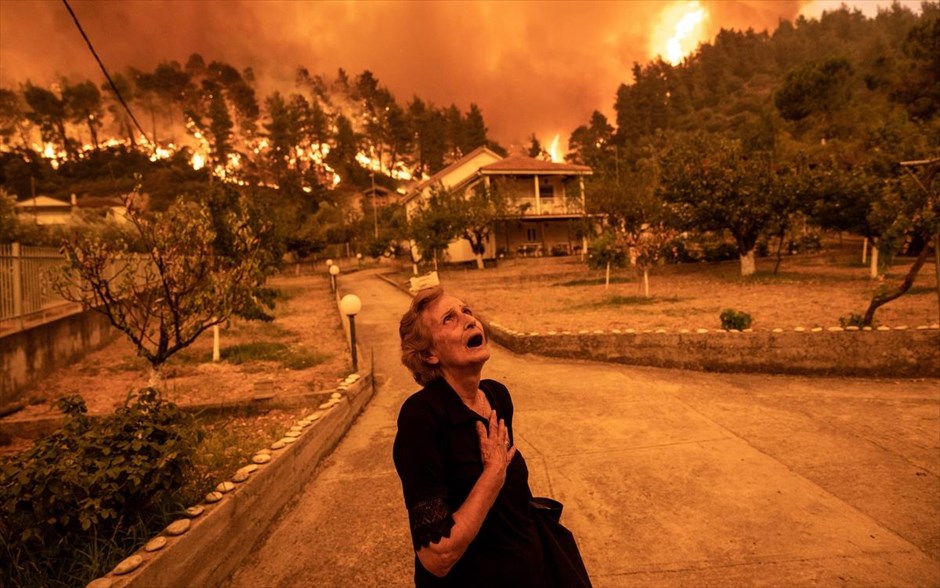 POY 2021. Μια ηλικιωμένη γυναίκα αντιδράει βλέποντας τη φωτιά να πλησιάζει στο χωριό Γούβες της Εύβοιας.