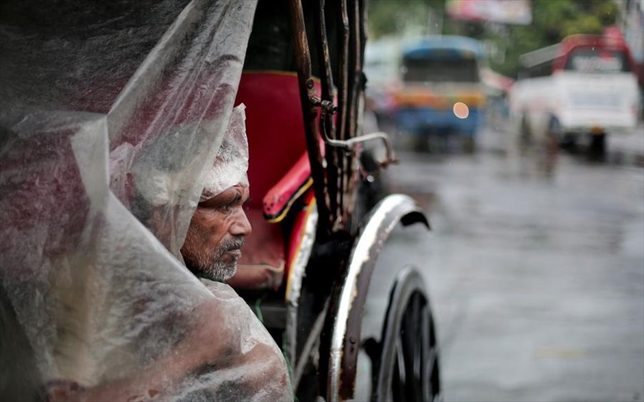 Περιμένοντας πελάτες. Ένας οδηγός ποδήλατου-ταξί περιμένει πελάτες κατά τη διάρκεια βροχερής ημέρα στην Καλκούτα της Ινδίας. 