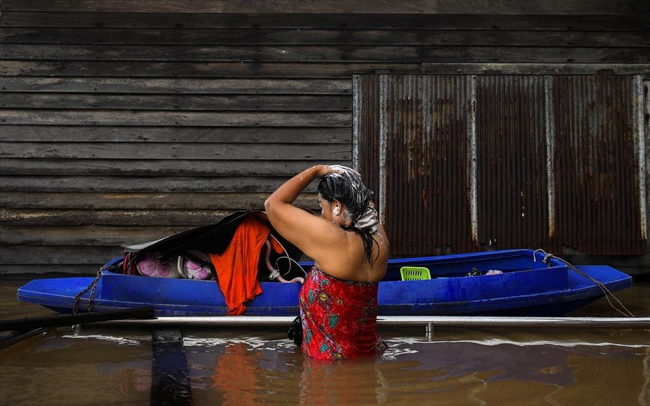 Μπάνιο σε... πλημμυρισμένο δρόμο. Μια γυναίκα κάνει μπάνιο σε έναν πλημμυρισμένο δρόμο μετά από έντονη βροχόπτωση κοντά στο τέμενος Tha-it στην επαρχία Νοντάμπουρι, στα περίχωρα της Μπανγκόκ, στην Ταϊλάνδη. 