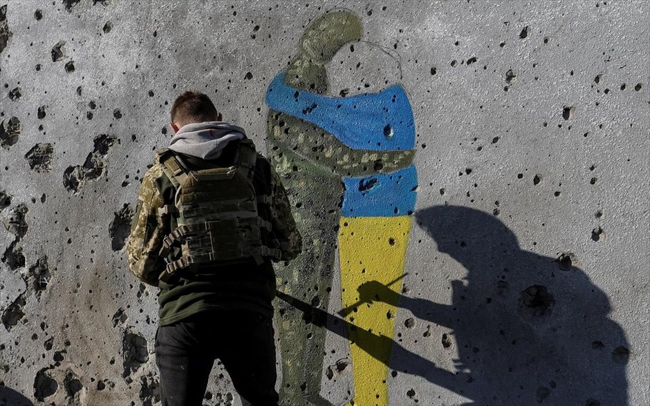Η τέχνη επιβιώνει. Ένας Ουκρανός καλλιτέχνης ζωγραφίζει τον τοίχο ενός κτιρίου, στο Κουπιάσνκ. Ο τοίχος έχει ίχνη από σφαίρες και σκάγια. 