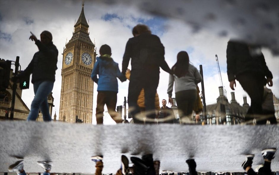 Αντανακλάσεις στο Λονδίνο. Το Μπιγκ Μπεν, στο Λονδίνο, αντανακλάται στο νερό μιας λακκούβας καθώς κόσμος περπατά έξω από τα κτήρια του Κοινοβουλίου. 