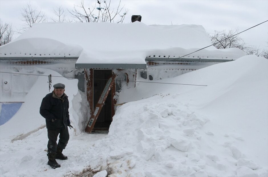 Πολικό ψύχος μαστίζει Ρωσία και Ουκρανία #8. Κάτοικος της πόλης Μπρόντι που απέχει 460 χλμ. Δυτικά του Κιέβου, προσπαθεί να απεγκλωβίσει το σπίτι του από το χιόνι.