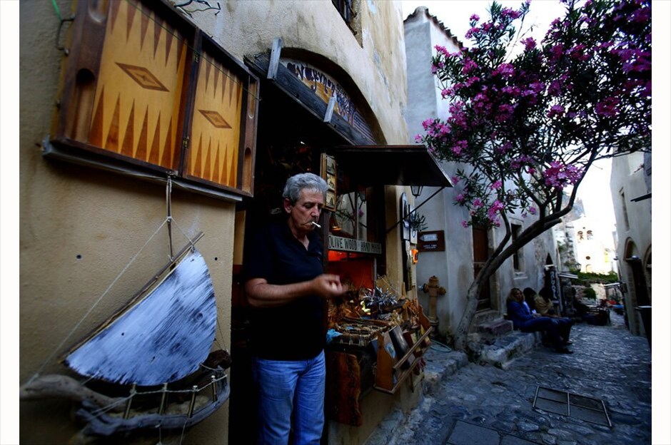 Ο ελληνικός τουρισμός στη σκιά της κρίσης #12. Ο Θεόδωρος Κώνστας, 53 ετών, καπνίζει έξω από το μαγαζί του στο μεσαιωνικό κάστρο της Μονεμβασιάς. Ο κ. Κώνστας έχει ένα μαγαζί με ξυλόγλυπτα είδη και είναι απαισιόδοξος για την οικονομική κατάσταση στην Ελλάδα. «Νομίζω ότι τα πράγματα θα χειροτερέψουν μετά τις εκλογές της 17ης Ιουνίου» αναφέρει – 29 Μαΐου 2012./