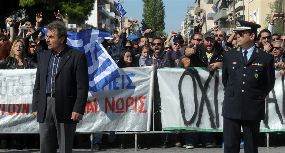 Διαμαρτυρίες και ματαιώσεις παρελάσεων σε πολλές πόλεις σε όλη την Ελλάδα #46. Στρατιωτική και μαθητική παρέλαση στην Κόρινθο με αισθητή την παρουσία των αγανακτισμένων και την απουσία των πολιτικών Αρχών, αρκετοί από τους μαθητές γύρισαν τα κεφάλια τους προς την απέναντι πλευρά των επίσημων όπου παρευρίσκονταν το πλήθος των αγανακτισμένων.