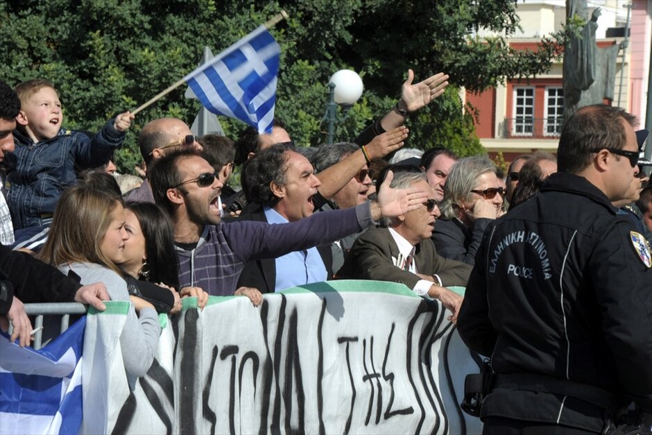 Διαμαρτυρίες και ματαιώσεις παρελάσεων σε πολλές πόλεις σε όλη την Ελλάδα #48. Στρατιωτική και μαθητική παρέλαση στην Κόρινθο με αισθητή την παρουσία των αγανακτισμένων και την απουσία των πολιτικών Αρχών, αρκετοί από τους μαθητές γύρισαν τα κεφάλια τους προς την απέναντι πλευρά των επίσημων όπου παρευρίσκονταν το πλήθος των αγανακτισμένων.