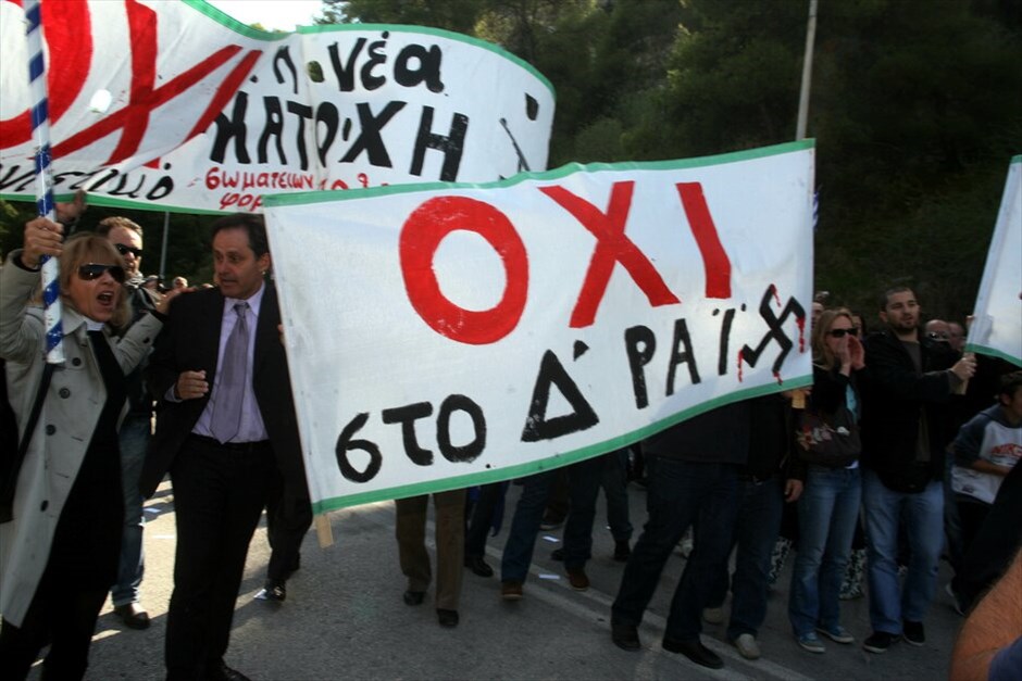 Διαμαρτυρίες και ματαιώσεις παρελάσεων σε πολλές πόλεις σε όλη την Ελλάδα #57. Διαμαρτυρία πολιτών κατά του υφυπουργού Περιβάλλοντος Γιάννη Μανιάτη στην παρέλαση για την Επέτειο της 28ης Οκτωβρίου στο Ναύπλιο.