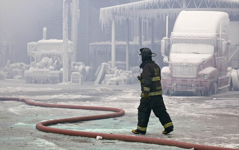Φωτιά σε αποθήκη στο Σικάγο #4. Ενας πυροσβέστης περνάει μπροστά από μία αποθήκη καλυμμένη από πάγο, που έπιασε φωτιά την Τρίτη το βράδυ στο Σικάγο, 22 Ιανουαρίου 2013.