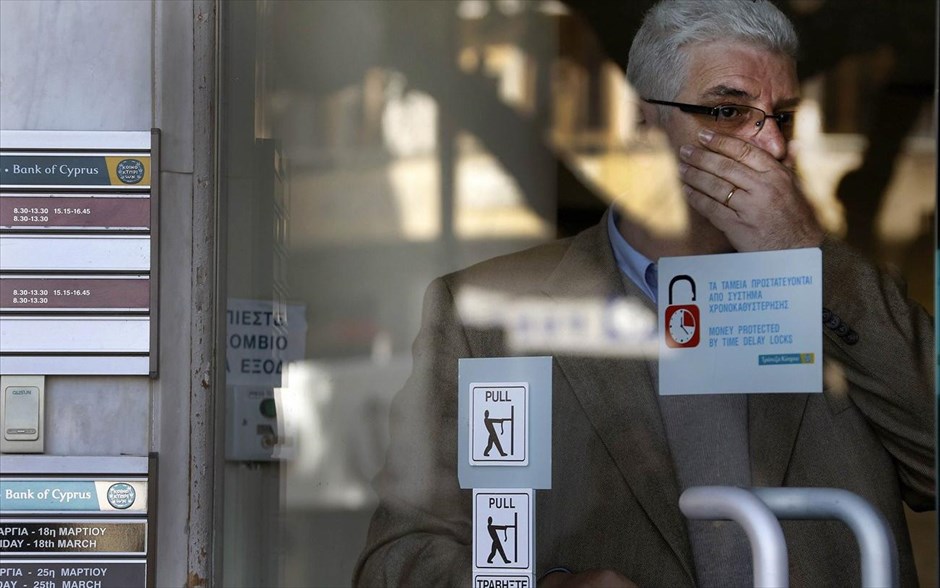 Ανοίγουν το μεσημέρι οι τράπεζες στην Κύπρο. Ενας υπάλληλος αντιδρά καθώς κοιτάζει τον κόσμο και τους δημοσιογράφους που έχουν μαζευτεί έξω από το υποκατάστημα της τράπεζας Κύπρου λίγο πριν ανοίξει, στη Λευκωσία. Στην αντίδραση των πολιτών και κυρίως των ξένων καταθετών στρέφεται η προσοχή στην Κύπρο, όπου επαναλειτουργούν σήμερα, μετά από σχεδόν δύο εβδομάδες, οι τράπεζες, υπό δρακόντειους περιορισμούς στην κίνηση κεφαλαίων.