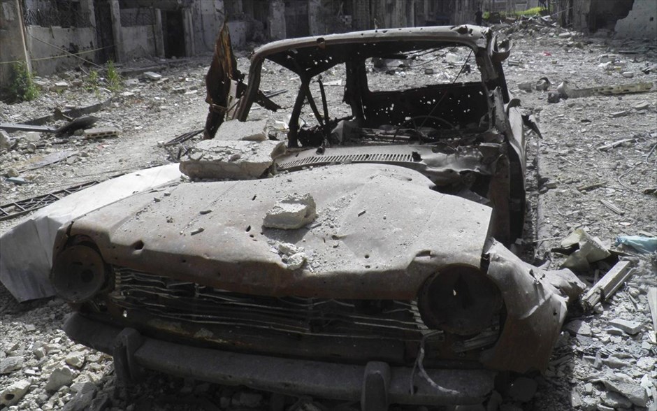 Πόλεις  - συντρίμμια στη Συρία. Κατεστραμμένο όχημα σε δρόμο γεμάτο από ερείπια σε συνοικία της πόλης Χομς. 8 Απριλίου 2013.