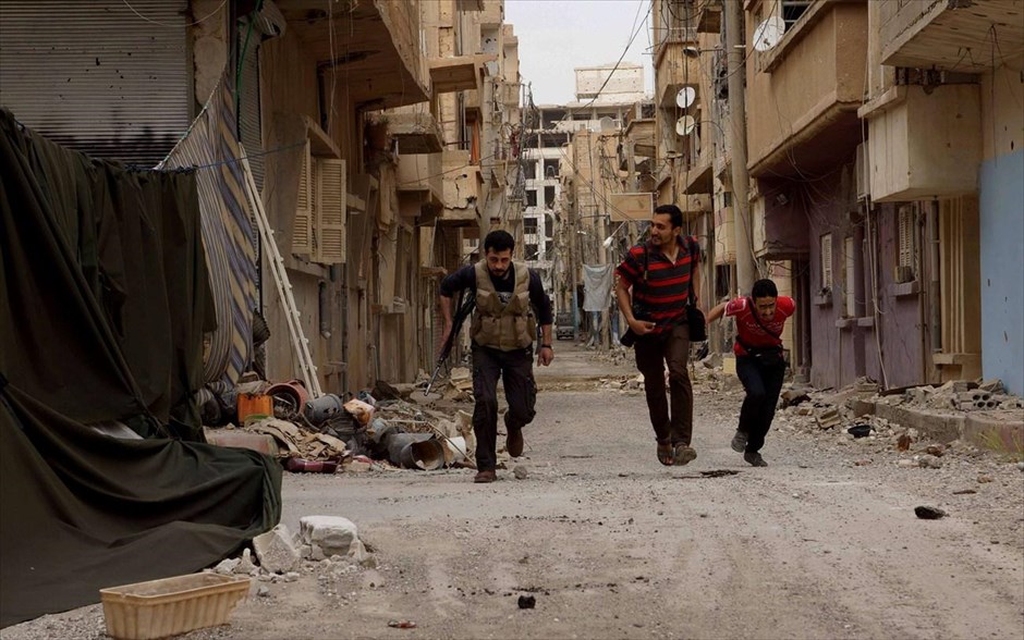 Πόλεις  - συντρίμμια στη Συρία. Τρεις άνδρες τρέχουν να προστατευθούν από τα πυρά δυνάμεων του καθεστώτος στην περιοχή Ντείρ Αλ-Ζορ της Ανατολικής Συρίας. 9 Απριλίου 2013.