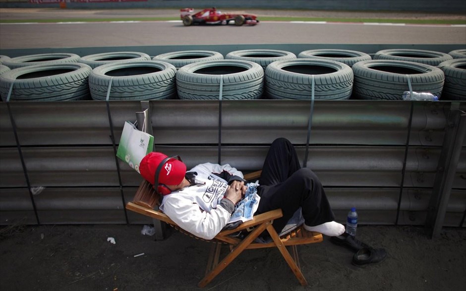 H Formula 1 στη Σαγκάη . Τεχνικός αγώνων κοιμάται καθώς ο οδηγός της Formula 1 Φερνάντο Αλόνσο, τον προσπερνάει κατά τη διάρκεια του δεύτερου δοκιμαστικού του Γκραν Πρι της Κίνας στο Shanghai International Circuit.