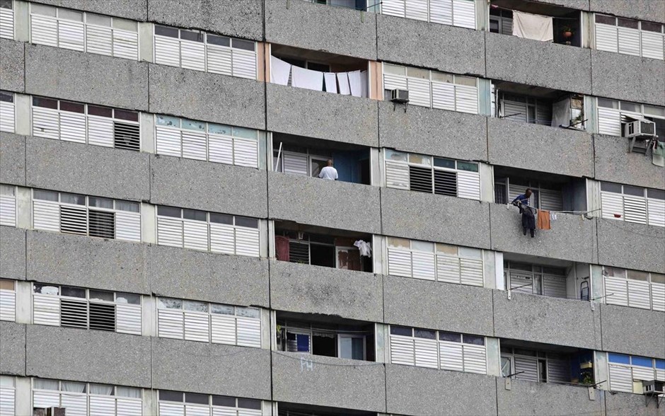 Αβάνα: Ενα αρχιτεκτονικό «στολίδι» υπό εγκατάλειψη #3. Ενας άντρας στέκεται στο μπαλκόνι του διαμερίσματός του σε ένα κτίριο σοβιετικής εποχής, στην Αβάνα.