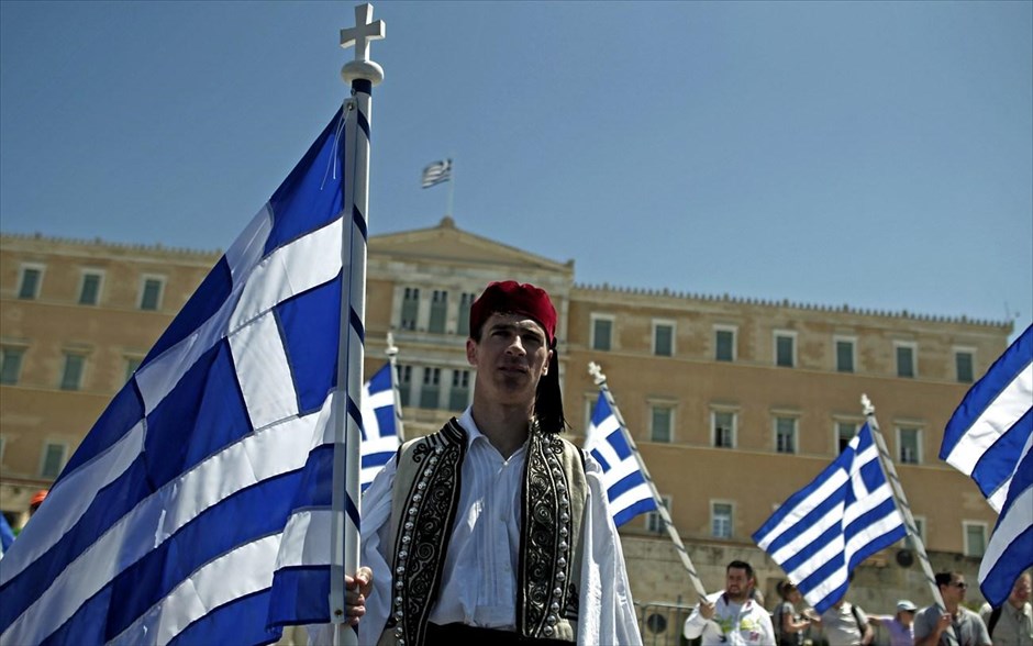 Συμβασιούχοι: Στους δρόμους κατά του πολυνομοσχεδίου. Διαδηλωτής ντυμένος με την παραδοσιακή στολή του τσολιά κρατά την ελληνική σημαία, καθώς συμβασιούχοι του Δημοσίου και εργαζόμενοι της ΠΟΕ-ΟΤΑ διαμαρτύρονται έξω από τη Βουλή με αφορμή τη συζήτηση για τη ψήφιση του νέου πολυνομοσχεδίου.