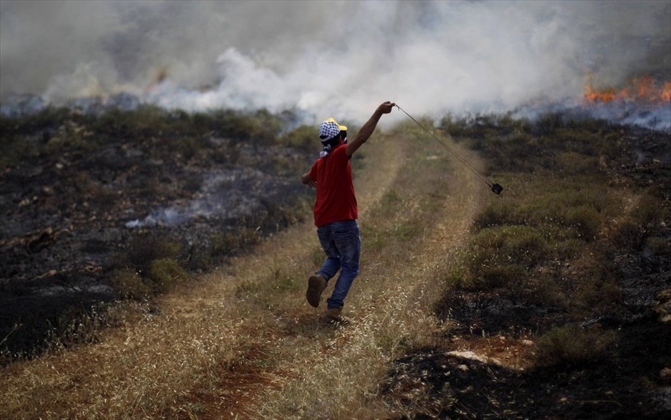 Με πέτρες και σφεντόνες. Παλαιστίνιος διαδηλωτής χρησιμοποιεί μία σφεντόνα για να ρίξει πέτρες εναντίον ισραηλινών στρατευμάτων, κατά τη διάρκεια συγκρούσεων σε χωριό της Λωρίδας της Γάζας κοντά στη Ραμάλα.
