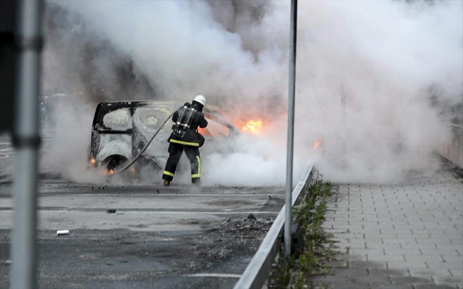 Σουηδία: Επεισόδια στη Στοκχόλμη #3. Πυροσβέστες προσπαθούν να κατασβήσουν τη φωτιά σε αυτοκίνητο κατά τη διάρκεια επεισοδίων νεαρών διαδηλωτών στα φτωχά προάστια της Στοκχόλμης, όπου ζουν πολλοί ξένοι.