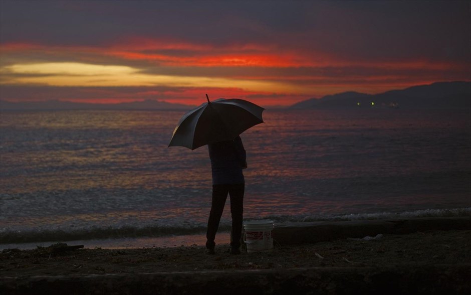 Ηλιοβασίλεμα με βροχή. Μία γυναίκα στέκεται στη βροχή κατά το ηλιοβασίλεμα στο δυτικό Βανκούβερ του Καναδά.