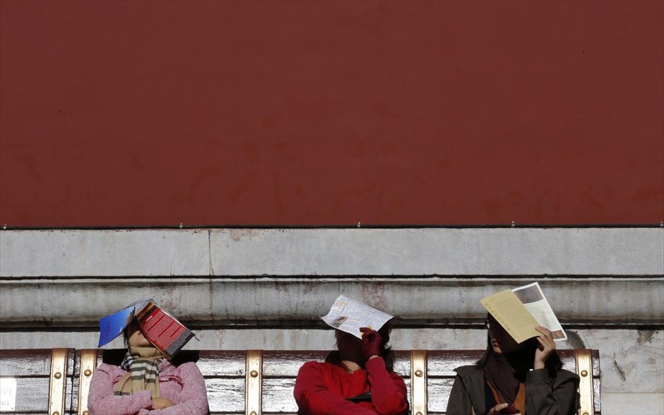 Κίνα: Ξενάγηση στην Απαγορευμένη Πόλη. Γυναίκες καλύπτουν τα κεφάλια τους με εφημερίδες για να προστατευτούν από τον ήλιο, καθώς ξεκουράζονται σε ένα παγκάκι κατά την ξενάγησή τους στην Απαγορευμένη Πόλη στο Πεκίνο.