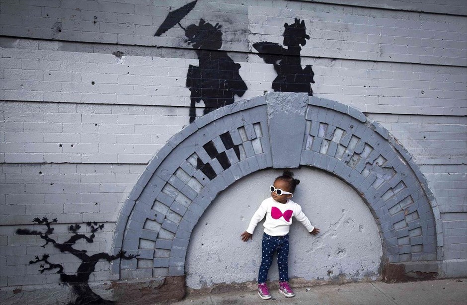 Ο Banksy συνεχίζει να «διακοσμεί» τη Νέα Υόρκη. Ενα παιδί στέκεται μπροστά από ένα νέο γκράφιτι του βρετανού καλλιτέχνη Banksy, στο Μπρούκλιν, στη Νέα Υόρκη. Ο Banksy τράβηξε την προσοχή του δημάρχου της Νέας Υόρκης Μάικλ Μπλούμπεργκ, ο οποίος δήλωσε ότι το γκράφιτι καταστρέφει τη δημόσια περιουσία. «Είναι δείγμα παρακμής και απώλειας ελέγχου» ανέφερε, σύμφωνα με τα τοπικά μέσα.