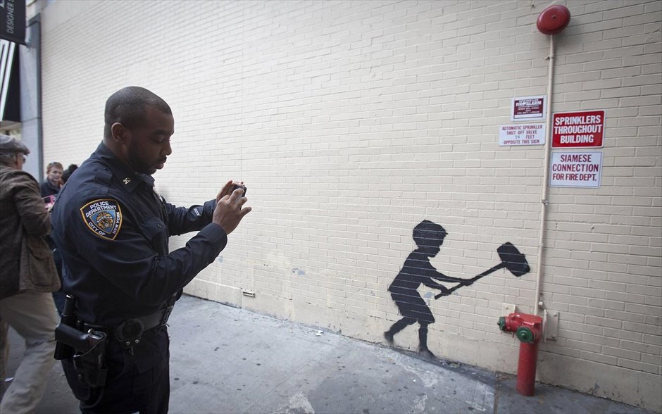 O Banksy κατακτά τη Νέα Υόρκη #20. Αστυνομικός βγάζει φωτογραφία ενός νέου έργου του Banksy στη Νέα Υόρκη, 20 Οκτωβρίου 2013.