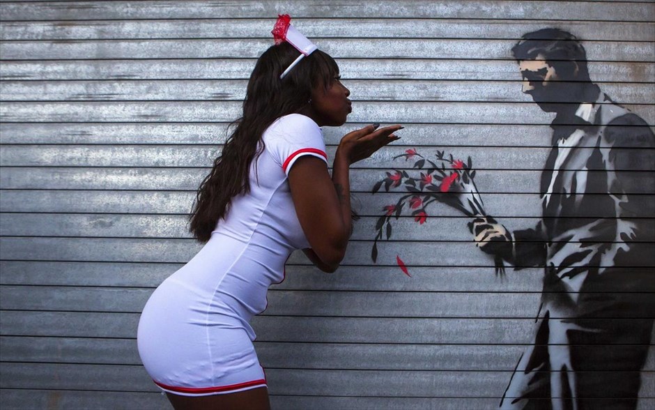 O Banksy κατακτά τη Νέα Υόρκη #26. Χορεύτρια ποζάρει για φωτογραφία δίπλα στο νέο γκράφιτι του Banksy έξω από το Hustler Club στηΝέα Υόρκη, 24 Οκτωβρίου 2013.