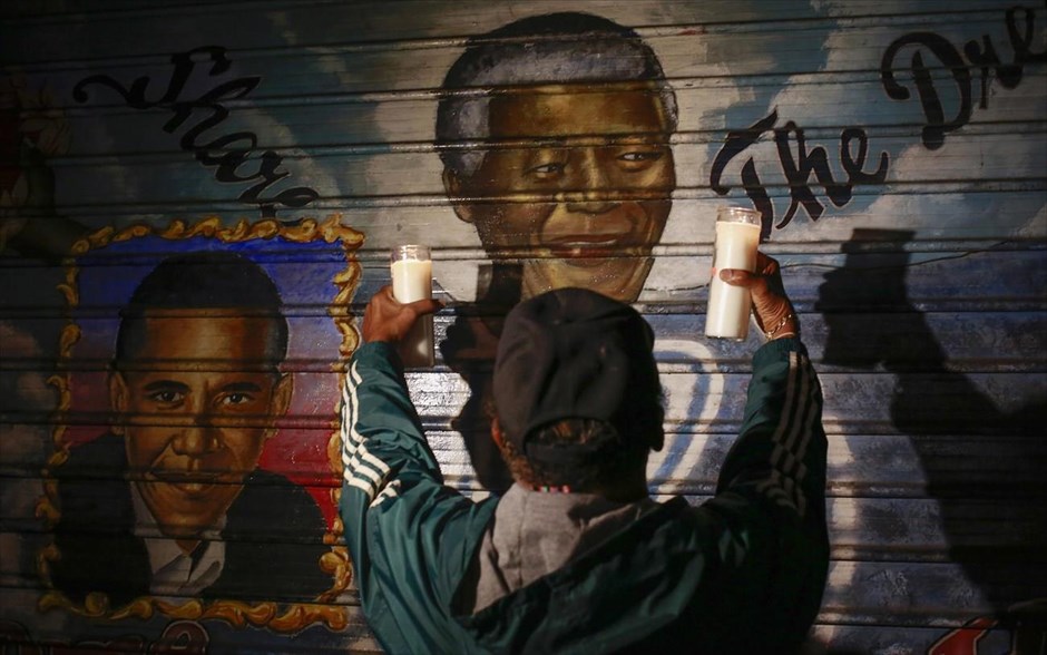 Νέλσον Μαντέλα. Ένας άνδρας κρατά κεριά μπροστά από ένα γκράφιτι με τα πρόσωπα του Νέλσον Μαντέλα και του Μπαράκ Ομπάμα (αριστερά) στη Νέα Υόρκη.