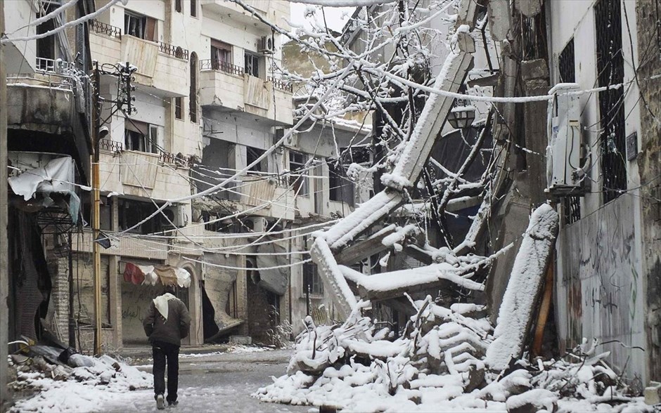 Συρία - Κακοκαιρία. Ενας άντρας περπατά ανάμεσα σε συντρίμια κατεστραμένων κτηρίων καλυμμένων με χιόνι στη Χομς.
