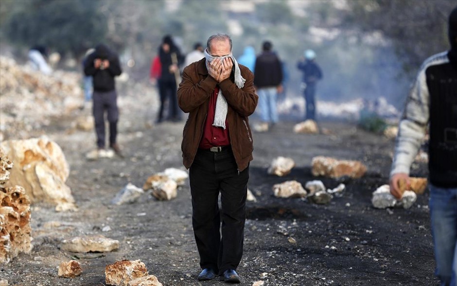 Συγκρούσεις στη Δυτική Όχθη. Ένας Παλαιστίνιος καλύπτει το πρόσωπό, προκειμένου να προστατευθεί από δάκρυγονα, κατά τη διάρκεια συγκρούσεων μεταξύ του ισραηλινού στρατού και Παλαιστίνιων, που ξέσπασαν μετά την κηδεία του 85χρονου Saeed Jaser Ali, στο χωριό Kufr Kadum στη Δυτική Όχθη. Ο Ali πέθανε την Πέμπτη, αφότου εισέπνευσε δακρυγόνα που είχε ρίξει ο ισραηλινός στρατός για να διαλύσει μία διαδήλωση, σύμφωνα με μάρτυρες. 