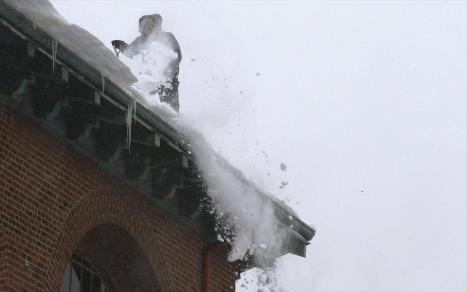 ΗΠΑ - κακοκαιρία - χιόνι. Άντρας φτυαρίζει το χιόνι από την στέγη κτηρίου στη Βοστόνη.