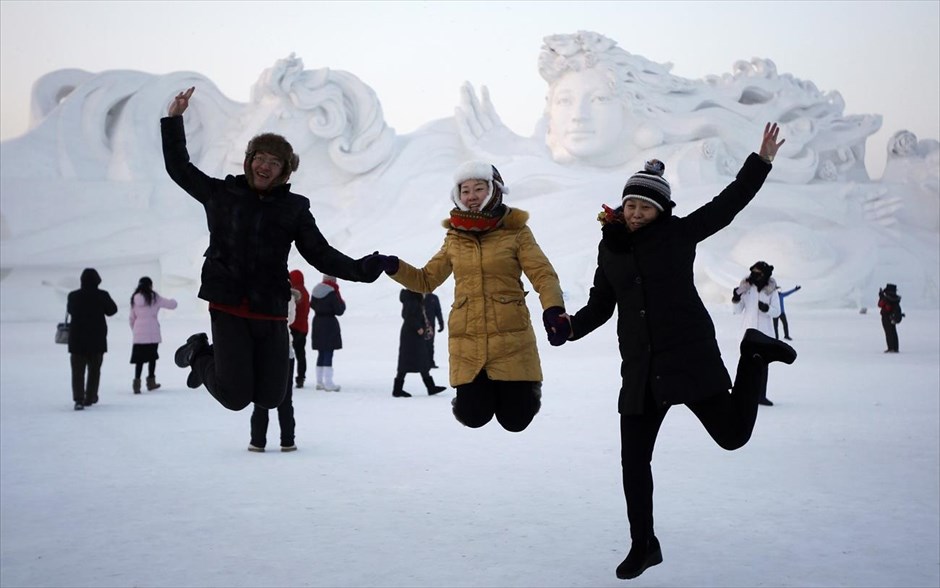 Κίνα: Περιήγηση ανάμεσα σε γλυπτά από πάγο. Επισκέπτες ποζάρουν για φωτογραφία μπροστά από ένα γιγάντιο γλυπτό από χιόνι, στο Διεθνές Φεστιβάλ Παγου και Χιονιού στο Χαρμπίν, στην επαρχία Χεϊλονγκτζιάνγκ.