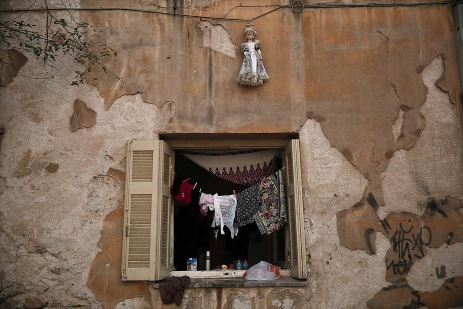 Τα «Προσφυγικά» της λεωφόρου Αλεξάνδρας. Μία κούκλα είναι κρεμασμένη στον τοίχο πάνω από ένα παράθυρο, σε ένα από τα διαμερίσματα των «Προσφυγικών» της λεωφόρου Αλεξάνδρας. Το συγκρότημα πολυκατοικιών, που έχει ακόμα τα σημάδια από τις σφαίρες των Δεκεμβριανών του 1944 και έχει απειληθεί με κατεδάφιση, είχε καλυφθεί με ένα τεράστιο πανί κατά τη διάρκεια των Ολυμπιακών Αγώνων του 2004. Σήμερα, καθώς η Ελλάδα διανύει τον 6ο χρόνο ύφεσης και οι άστεγοι της Αθήνας υπολογίζονται περίπου στις 20.000, σύμφωνα με εκτιμήσεις των ΜΚΟ, τα διαμερίσματα που προορίζονταν αρχικά για πρόσφυγες από τη Μικρά Ασία, αποτελούν πλέον καταφύγιο για καταληψίες, ναρκομανείς καθώς και μετανάστες.