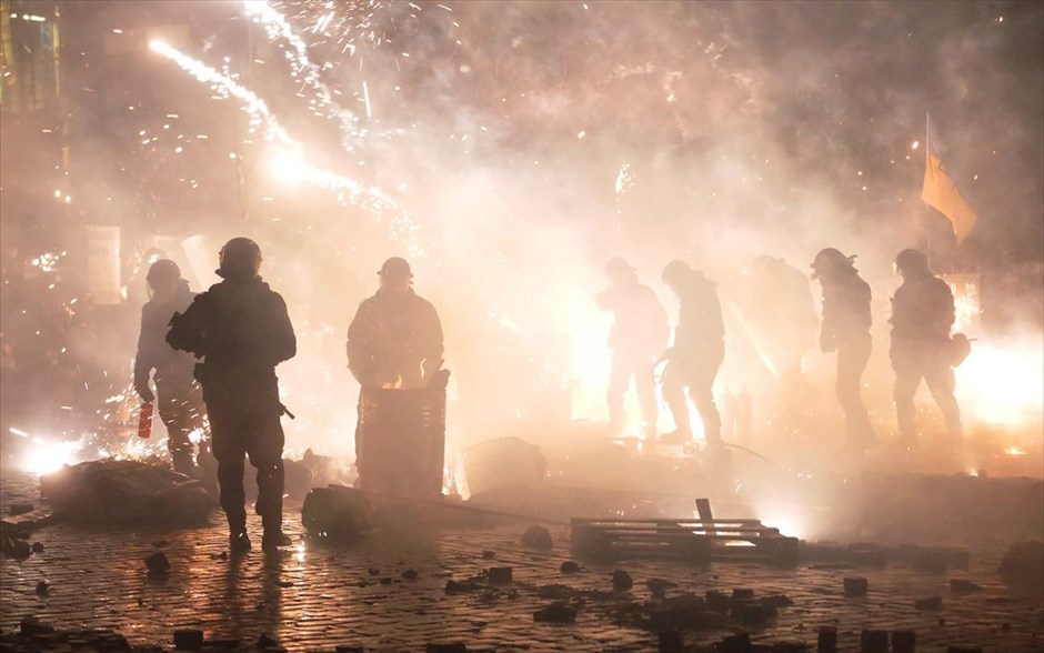 Ουκρανία - Συγκρούσεις στο Κίεβο. Ένα πυροτέχνημα, που πυροδότησαν οι διαδηλωτές, σκάει μπροστά από τους άνδρες της ουκρανικής αστυνομίας κατά τη διάρκεια συγκρούσεων τα ξημερώματα της Πέμπτης στο Κίεβο.