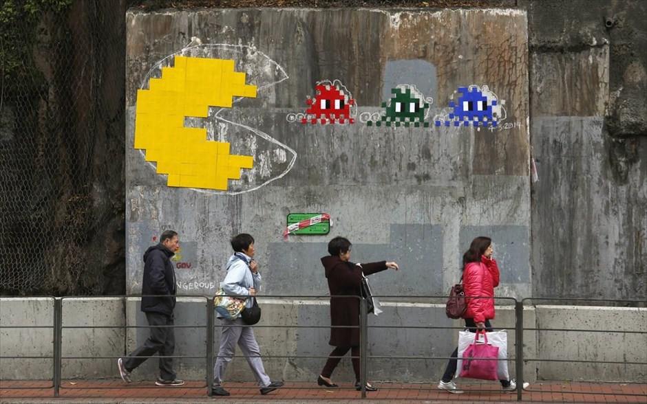 Το Pac-Man στο Χονγκ Κονγκ. Κόσμος περνά μπροστά από το αντίγραφο ενός έργου τέχνης του γάλλου αστικού καλλιτέχνη «Space Invader», στο Χονγκ Κονγκ. Το έργο, που απεικονίζει το γνωστό ηλεκτρονικό παιχνίδι Pac-Man, στην αυθεντική του μορφή ήταν στο ίδιο σημείο, αλλά αφαιρέθηκε από την κυβέρνηση του Χονγκ Κονγκ για λόγους «ασφάλειας» το Φεβρουάριο του 2013, σύμφωνα με τα τοπικά μέσα.