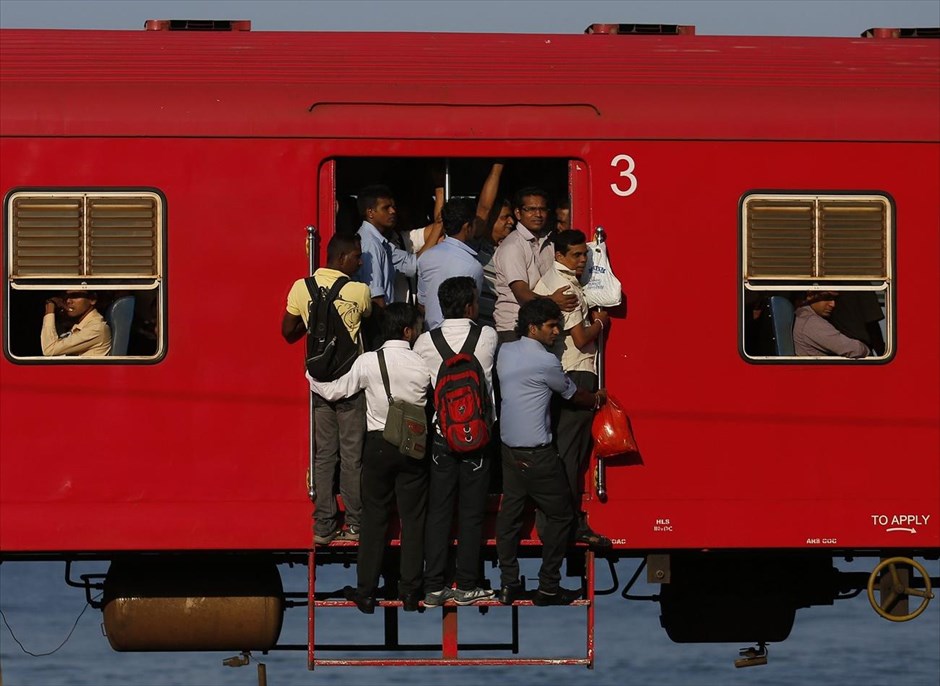 Επιβατικό τρένο στη Σρι Λάνκα. Επιβάτες κρατιούνται από τα χερούλια της πόρτας ενός βαγονιού, στοιβαγμένοι σε ένα γεμάτο από κόσμο τρένο, καθώς ταξιδεύουν για το Κολόμπο.