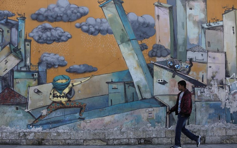 Στιγμιότυπο από το κέντρο της Αθήνας. Ένας άνδρας περπατά μπροστά από ένα τοίχο καλυμμένο με γράφιτι στο Γκάζι.