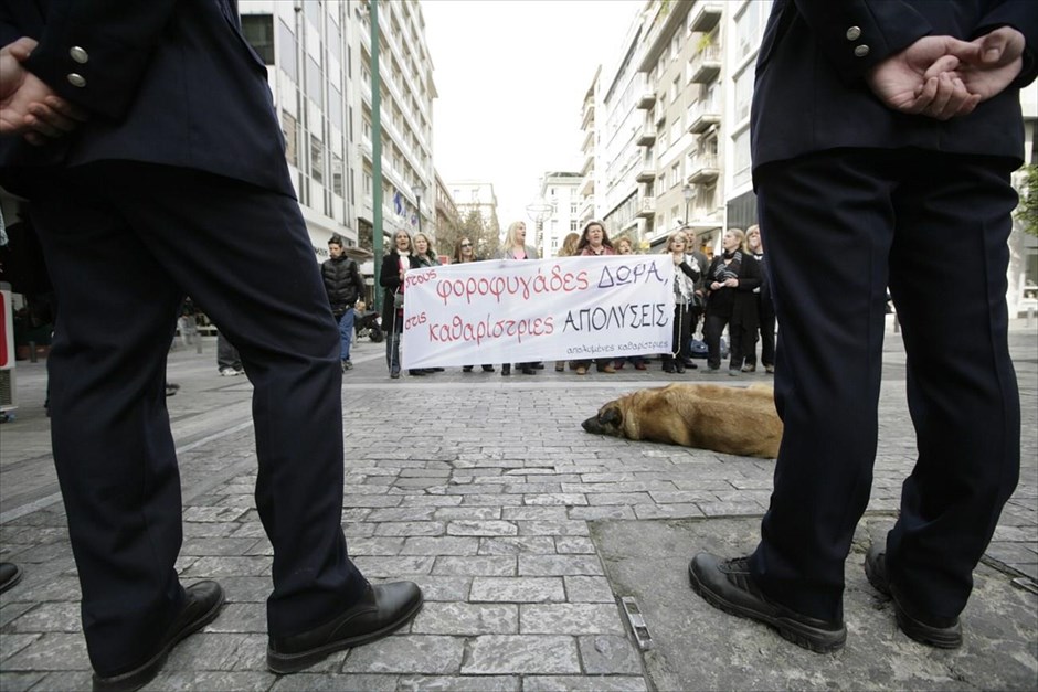Διαμαρτυρία των απολυμένων καθαριστριών του ΥΠΟΙΚ. Απολυμένες καθαρίστριες του υπουργείου Οικονομικών πραγματοποιούν διαμαρτυρία στην οδό Ερμού, φωνάζοντας συνθήματα και κρατώντας πανό. Η αστυνομία έκλεισε την Ερμού προκειμένου να αποτραπεί η πρόσβαση των διαμαρτυρόμενων στην παρέλαση.
